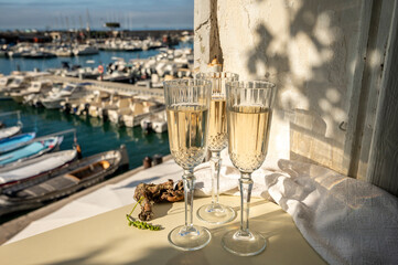 Three glasses of French champagne sparkling wine and view on colorful fisherman's boats in old harbour in Cassis, Provence, France