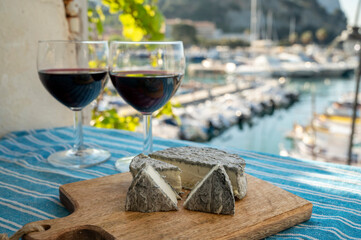 Summer party with red wine and cheeses on outdoor terrace with view on old fisherman's harbour with colourful boats in Cassis, Provence, France