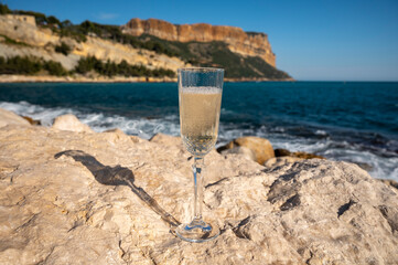 French champagne sparkling wine in glass and view on beach and mountains in Cassis, Provence, France