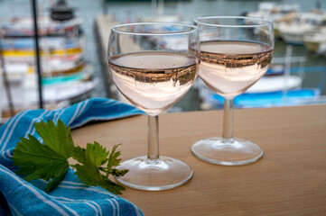 Rose wine in glasses served on outdoor terrace with view on old fisherman's harbour with colourful boats in Cassis, Provence, France