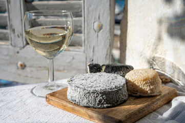 French goat cheeses crottin and selles-sur-cher served with view on boats in harbor of Cassis, Provence, France with glass of dry white wine