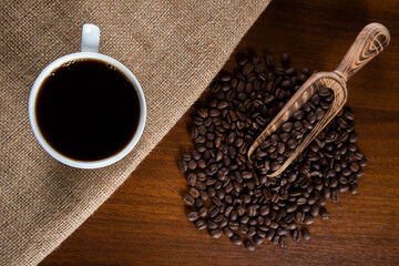 White cup of coffee with coffee beans on wooden background
