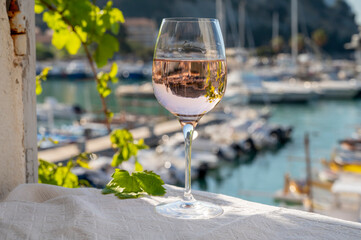 Rose wine in glass served on outdoor terrace with view on old fisherman's harbour with colourful...