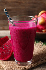 Glass of tasty pitahaya smoothie and fresh fruits on wooden table
