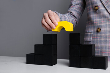 Businesswoman building bridge with colorful blocks at table, closeup. Connection, relationships and...