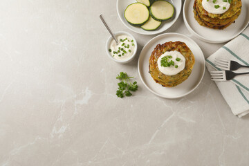 Delicious zucchini pancakes served on light grey table, flat lay. Space for text