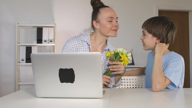Son of 12 years presents a bunch of flowers to the mother