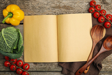 Recipe book surrounded by different ingredients on wooden table, flat lay with space for text....