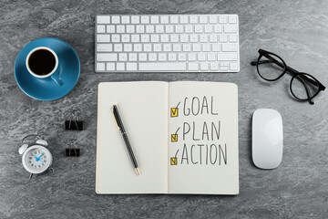 Flat lay composition of notebook with words Goal, Plan and Action on grey table