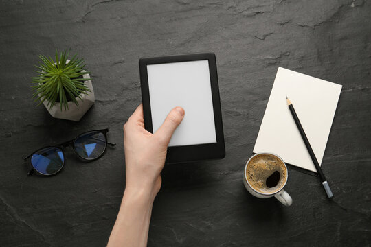 Woman using e-book reader at black table, top view