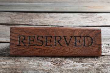 Elegant sign RESERVED on wooden surface. Table setting element