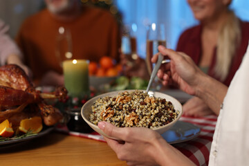 Woman with bowl of traditional Christmas Slavic dish kutia and her family at festive dinner