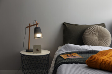 Stylish lamp and alarm clock on bedside table indoors. Bedroom interior elements - Powered by Adobe