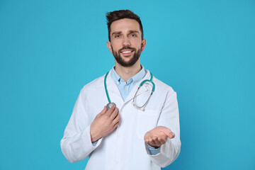 Fototapeta premium Doctor with stethoscope holding something on light blue background. Cardiology concept