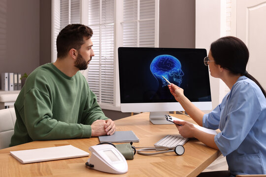 Neurologist showing brain scan to sad man in clinic
