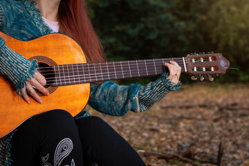 Joven mujer tocando la guitarra en el bosque