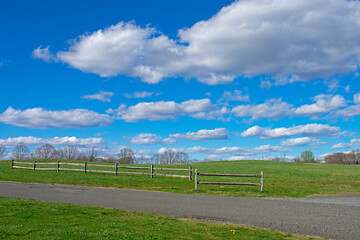 A sunny spring day with beautiful cumulus clouds over a fenced field at Big Brook Park, Marlboro, New Jersey -05