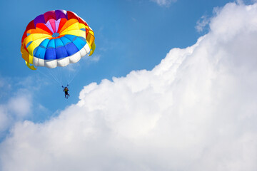 Paragliding using a parachute on background of blue cloudy sky.
