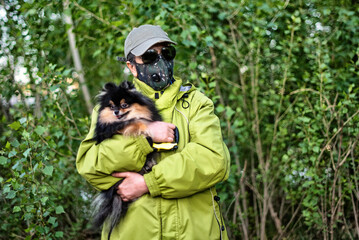 Obraz premium A girl wearing respirator mask walking with a Pomeranian dog in the forest protecting from COVID-19.