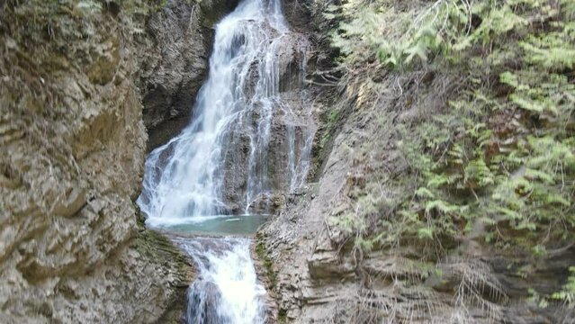 Margaret Falls cascading down a lush, mountain forest in the stunning Herald Provincial Park in British Columbia, Canada. Rising aerial shot 