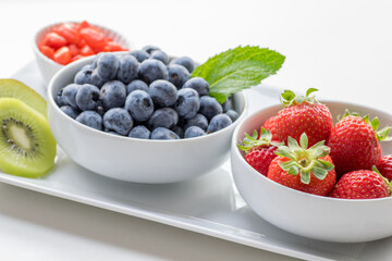 Organic Fresh Blueberries and Strawberries in White Bowls, White Background