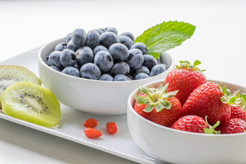 Organic Fresh Blueberries and Strawberries in White Bowls, White Background