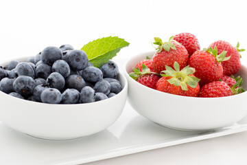 Organic Fresh Blueberries and Strawberries in White Bowls, White Background