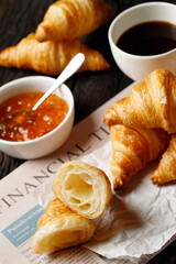 freshly baked croissants set of delicious fresh in wax paper plates on wooden dark table. French breakfast. top view Copy space.