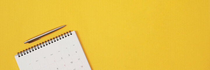 close up top view calendar schedule to make appointment meeting or manage timetable each day lay on yellow background for planning work and travel concept.