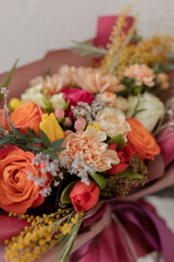 Bright bouquet in crimson paper. Orange roses, carnations, yellow tulips