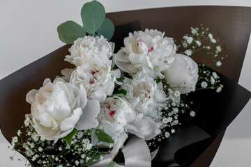 Bouquet with white peonies and eucalyptus in black packaging