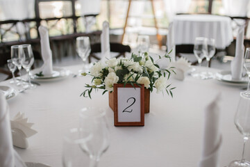 Decorated wedding table for guests with a number and a box of flowers