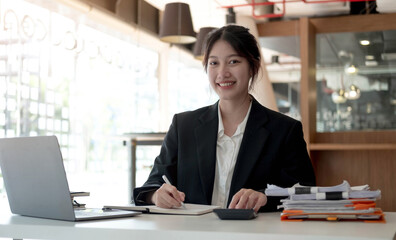Beautiful smiling Asian woman working at the office, looking at the camera.