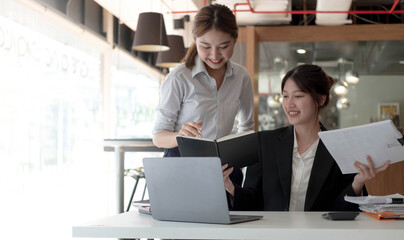 Two asian business woman work together to get the job done at the office.