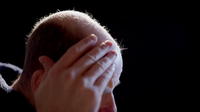 SLOW MOTION BACKLIT - A bald man inspects his pattern hair loss