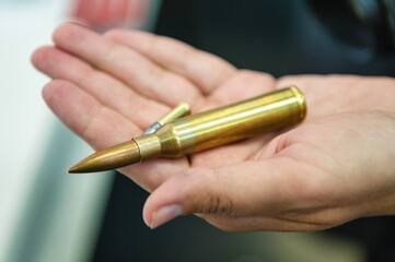 Hand holds small caliber and kalashnikov gun bullets closeup