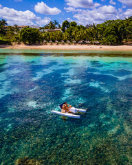 Paddleboards and pedalos on the idyllic palm fringed beach, couple men and woman on vacation...