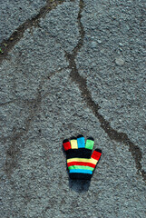 Fototapeta na wymiar Multi-colored children's glove on the pavement.