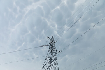 A steel power transmission pole against a backdrop of storm clouds.