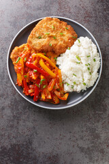 German schnitzel served with paprika sauce and rice close-up in a plate on the table. vertical top...