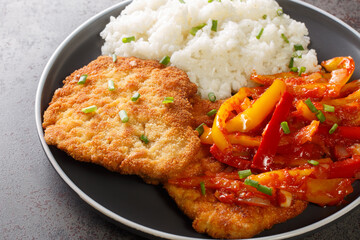 Paprika schnitzel served with a spicy Gypsy sauce of bell peppers and onions with rice as traditional German fast food in a plate on a table. Horizontal - obrazy, fototapety, plakaty