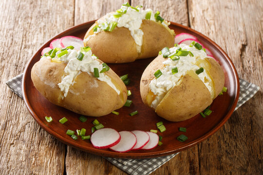 Classic Poznan specialty pyry z gzikiem is a simple potato and cheese dish close-up in a plate on a wooden table. Horizontal