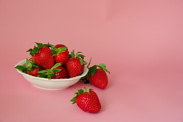 Strawberries in a white bowl against pink background