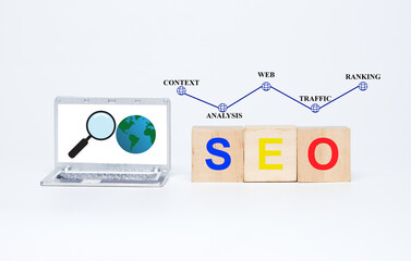 A picture of miniature laptop with magnifying and earth insight. SEO on wooden block. Context,...