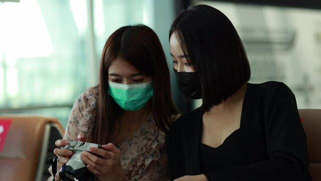 Two Asia women looking picture in a camera at the airport