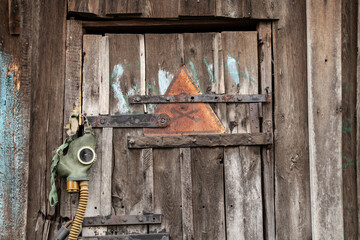An old gas mask and a dangerous sign with a painted skull hang on the door, gas attack in Ukraine...