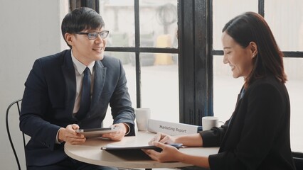 Happy two Asian young businessman and woman shaking hands greeting before meeting or negotiation with digital tablet sitting on desk cafe, Businesspeople discussion planning and smile lunch