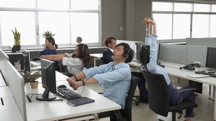 Call center is tired, young adult employee working with headset stretch while working hard,...