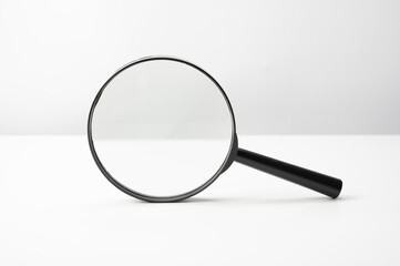 Magnifying glass black color on white table. Research, searching or investigating something. front...