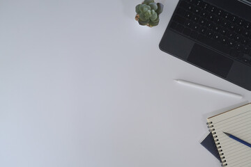 Top view minimal workplace with laptop computer, notebook and succulent plant on white table.